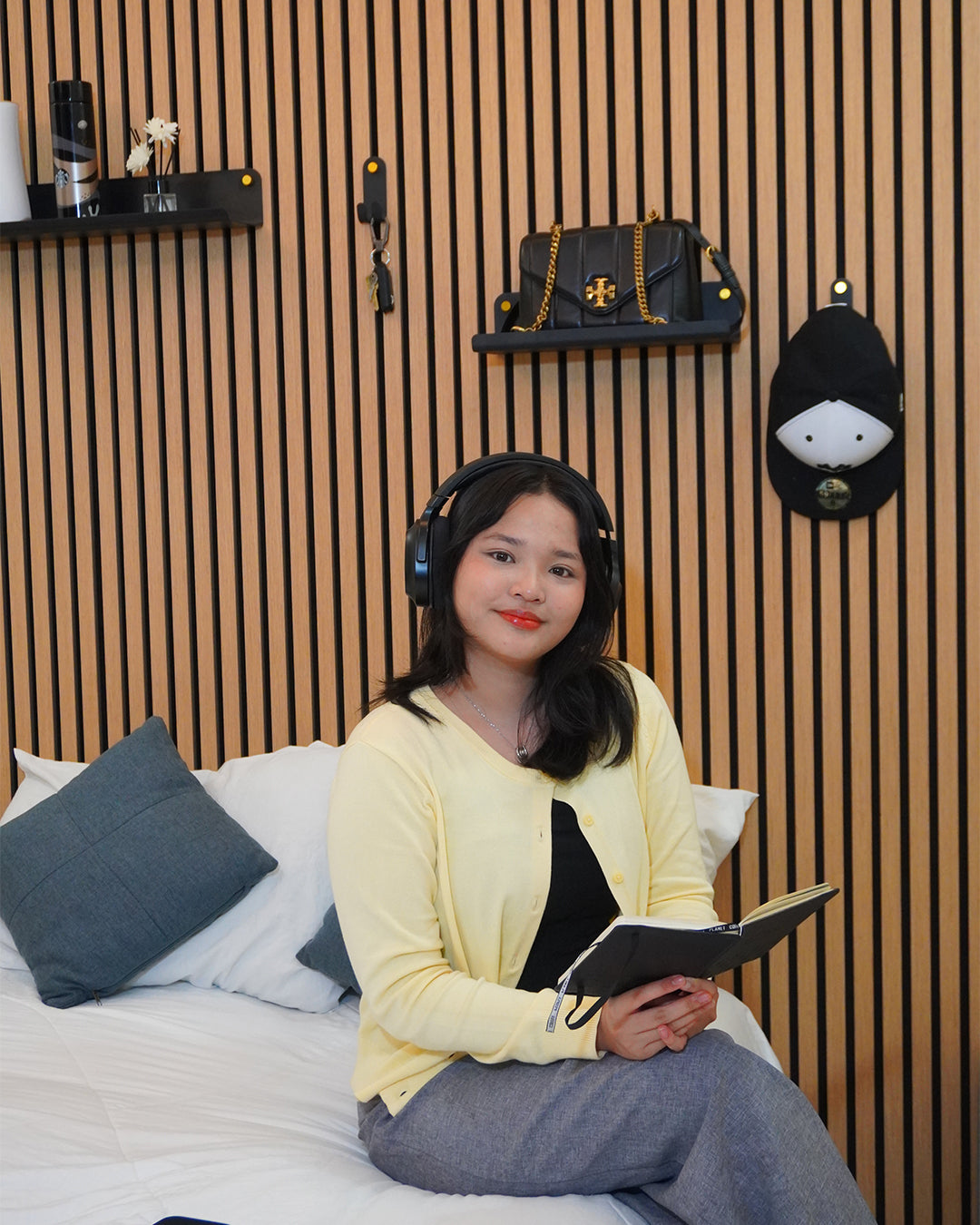 Woman wearing headphones and holding a book in a bedroom setting and Acoustic Panel Wide Shelf