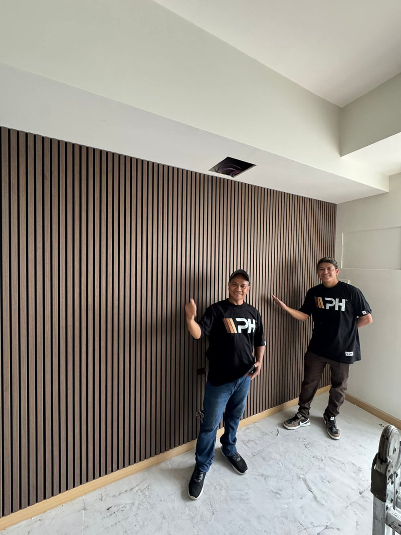 Wood Panel Philippines Contractor standing in a room with a modern interior design featuring a striped Acoustic Wall Panels.