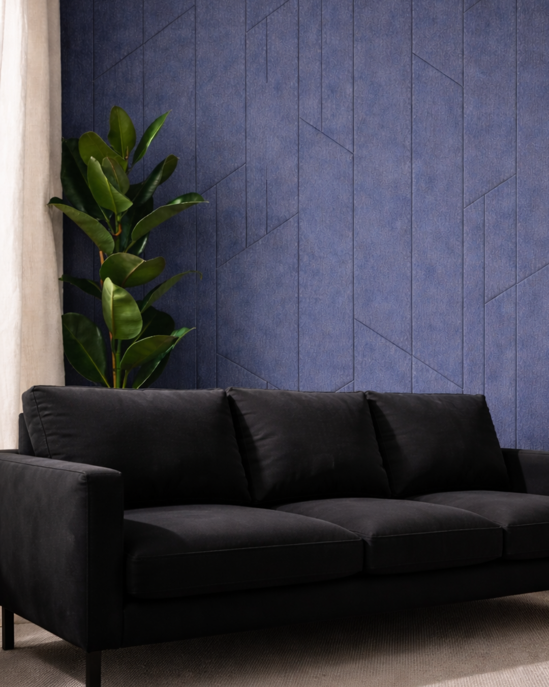 Black sofa against a blue Acoustic PET Panel with a plant on the left.