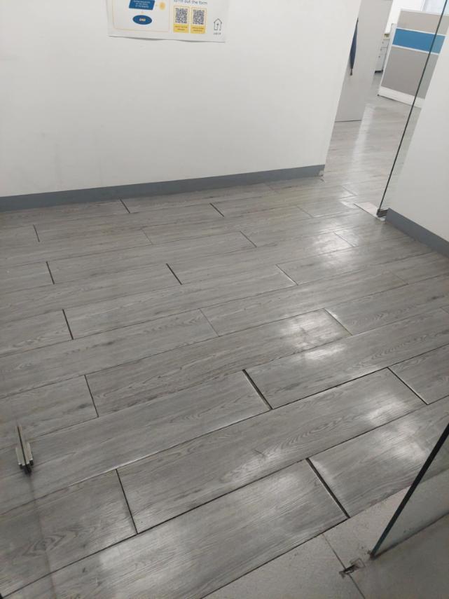 Gray Vinyl Flooring by Wood Panel Philippines with a white wall and glass partition in the background