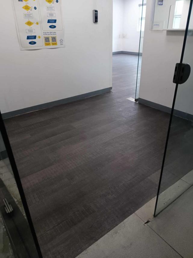 Glass door leading into a room with a Vinyl Flooring by Wood Panel Philippines and white walls.
