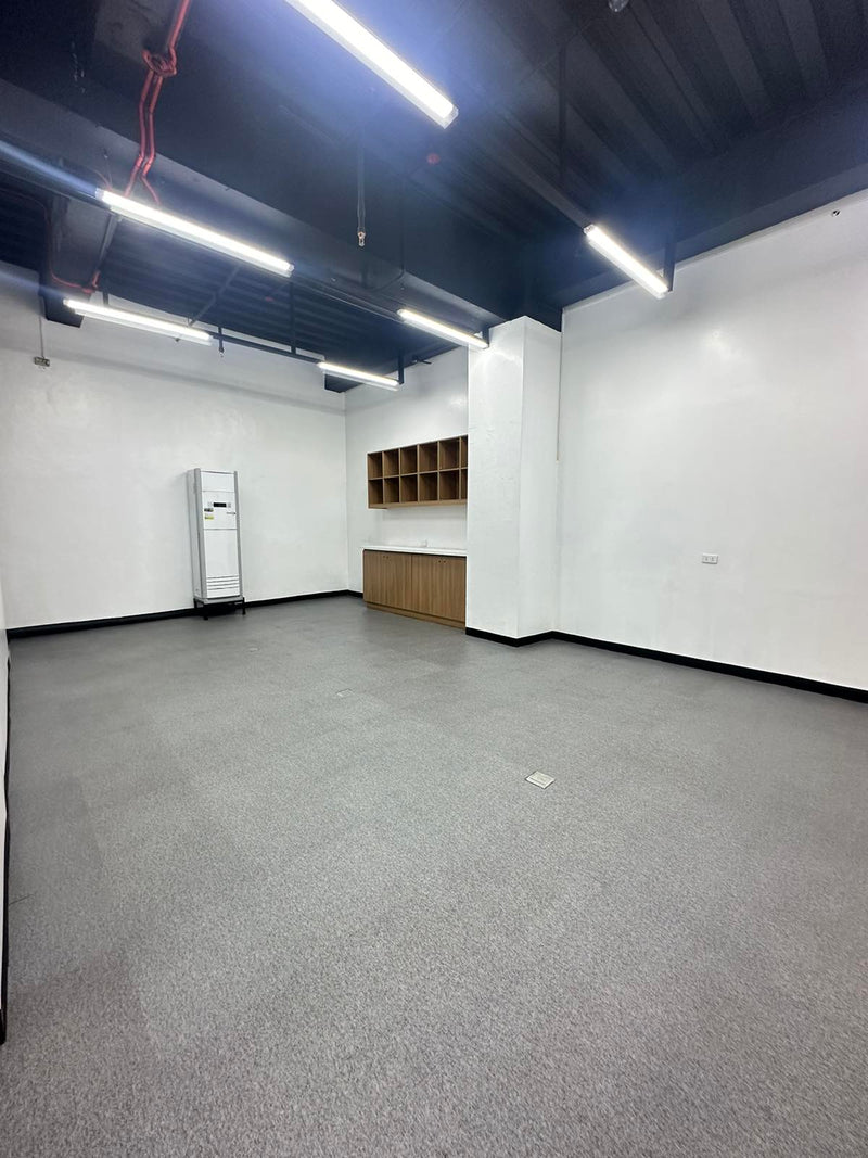 Empty room with white walls, gray carpet, and a small wooden shelf By Wood Panel Philippines
